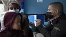 Seorang wanita, dengan anak di pangkuannya, divaksin COVID-19 di sebuah lokasi dekat Johannesburg, Rabu (8/12/2021). Kasus Omicron telah dikonfirmasi setidaknya di sembilan negara Afrika, dengan Afrika Selatan tetap menjadi episenter awal ditemukannya varian baru tersebut. (AP Photo/Denis Farrell)