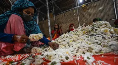 Seorang wanita membuat karangan bunga jelang Festival Diwali di pasar bunga New Delhi, India, Minggu (31/10/2021). Festival Diwali atau Festival Cahaya dalam agama Hindu melambangkan kemenangan baik atas buruk. (Money SHARMA/AFP)