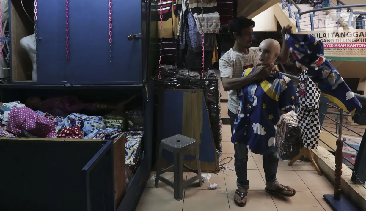 Seorang pedagang merapikan pakaian dagangannya yang dijual di Pasar Cipulir, Jakarta, Senin (6/4/2020). Penyebaran virus corona COVID-19 yang makin meluas sepekan terakhir membuat omzet para pedagang terjun bebas. (Liputan6.com/Johan Tallo)
