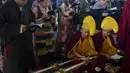 Biksu Buddha Tibet di pengasingan dengan topi upacara kuning membaca buku doa saat yang lain berdiri selama sesi doa pagi untuk menyambut Tahun Kelinci Air di Dharamshala, India, Selasa (21/2/2023). Losar tahun ini jatuh pada tanggal 21 Februari 2023. Menurut penanggalan Tibet, ini adalah awal tahun Kelinci Air 2150. (AP Photo/Ashwini Bhatia)