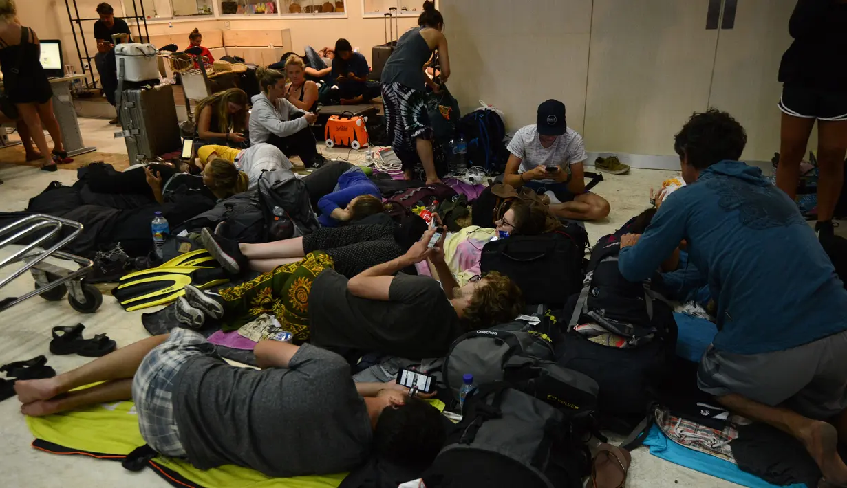 Wisatawan asing tidur di lantai saat menunggu jadwal keberangkatan pesawat di Bandara Internasional Praya Lombok, NTB, Senin (6/8). Imbas gempa 7 SR, para wisatawan terlantar di bandara karena jam pemberangkatan pesawat yang tertunda (AFP/SONNY TUMBELAKA)