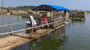 Warga menggunakan perahu  menyaksikan puing-puing  rumah yang kembali muncul di kawasan Bendungan Karian yang mengering di Kampung Somang, Lebak, Banten, Jumat, 7 Agustus 2026. (KLY/ Arie Basuki)