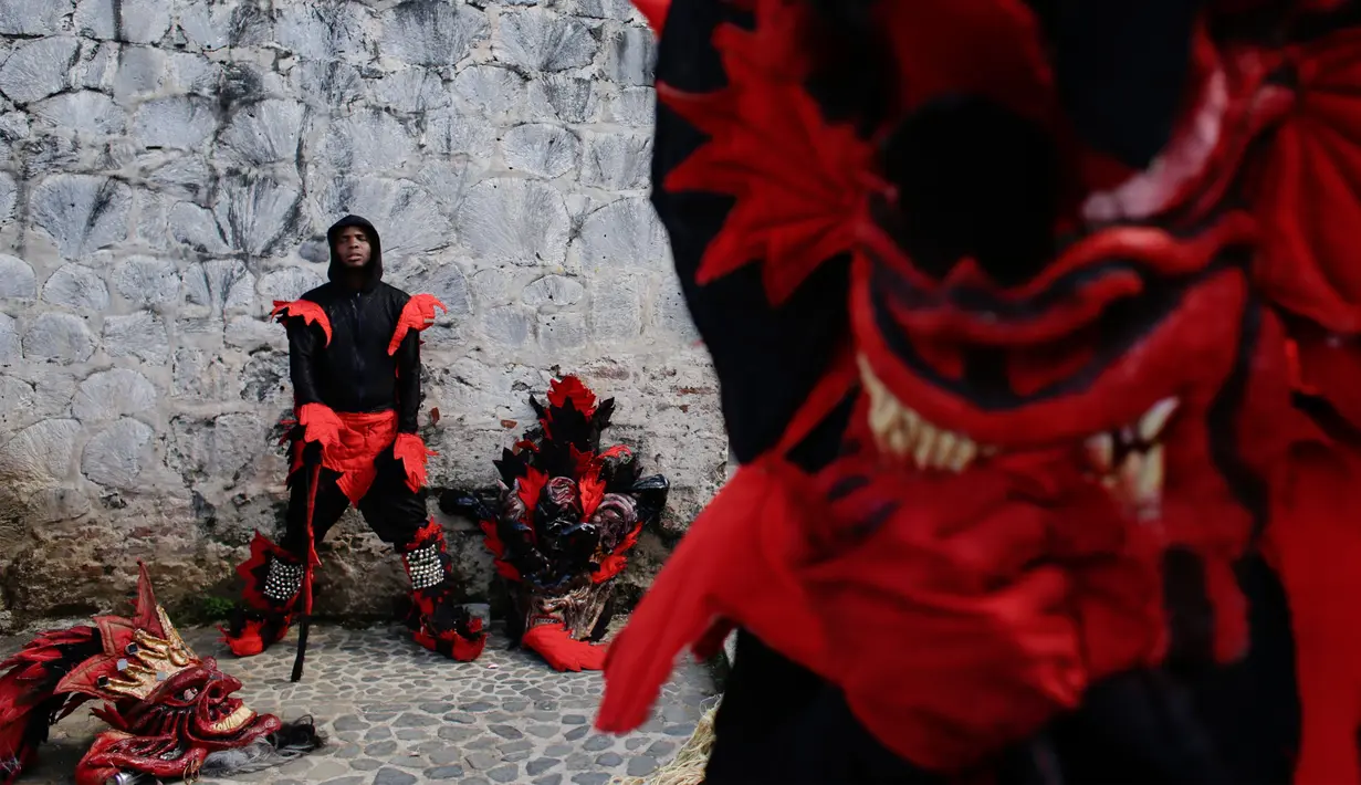 Seorang peserta mengenakan kostum setan beristirahat di sela-sela festival Congos and Devils di luar benteng San Jeronimo di Portobelo, Panama (18/3). (AP Photo/Arnulfo Franco)