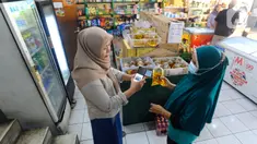 Pedagang melakukan scan KTP pembeli minyak goreng curah di Toko Tjandra, Cinere, depok, Jumat (03/06/2022). Paska dicabutnya kebijakan subsidi minyak goreng curah, pembeli minyak goreng curah di pasaran diwajibkan menyertakan kartu tanda penduduk (KTP) dengan maksimal 1 ktp untuk 2 liter minyak goreng curah seharga Rp 14.000/liter. (merdeka.com/Arie Basuki)