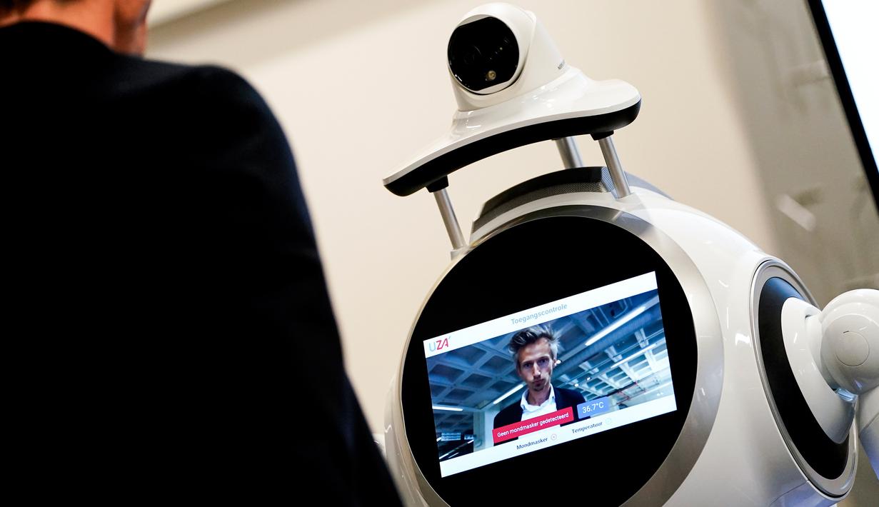 Seorang karyawan perusahaan Belgia, ZoraBots, menguji robot yang disebut CRUZR di Antwerp University Hospital (UZA) pada 29 Mei 2020. Robot ini dapat mendeteksi demam serta mengetahui pengunjung rumah sakit  yang memakai Masker atau tidak. (Kenzo TRIBOUILLARD/AFP)