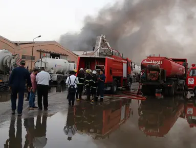 Pasukan keamanan dan pemadam berkumpul di lokasi kebakaran gudang surat suara terbesar Irak di Baghdad, Minggu (10/6). Gudang itu dilalap api sebelum dilakukan penghitungan kembali surat suara sebagaimana yang diperintahkan Parlemen. (AP/Karim Kadim)