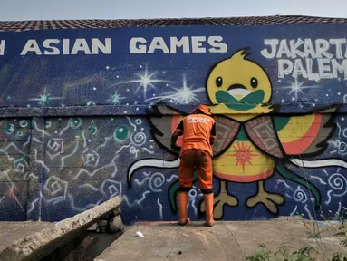 Petugas dari Penanganan Prasarana dan Sarana Umum (PPSU) membuat mural pada tembok yang berada di pinggir Jalan Landasan Pacu, Kemayoran, Jakarta, Rabu (11/7). (Merdeka.com/Iqbal S. Nugroho)