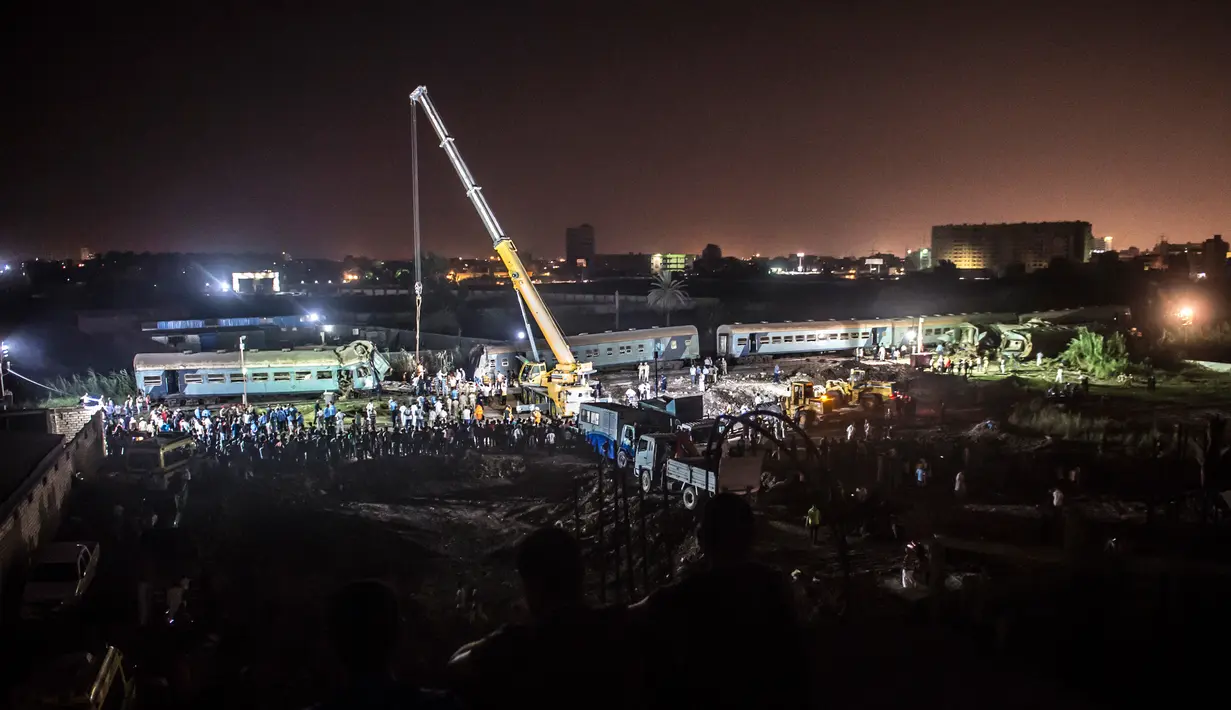 Petugas berusaha mengevakuasi bangkai kereta usai mengalami tabrakan di Kota Alexandria, Mesir (11/8). Akibat tabrakan dua kereta tersebut, sedikitnya 36 orang tewas dan 123 orang lainnya menderita luka. (AFP Photo/Khaled Deouki)