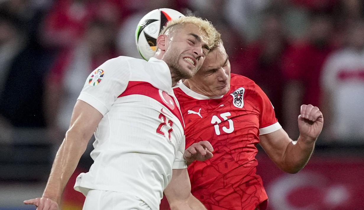 Striker Timnas Turki, Baris Alper Yilmaz (kiri) berduel udara dengan bek Timnas Austria, Philipp Lienhart pada laga babak 16 besar Euro 2024 di Red Bull Arena, Leipzig, Jerman, Rabu (3/7/2024). (AP Photo/Andreea Alexandru)