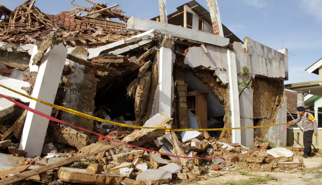 Seorang polisi memeriksa rumah yang runtuh gempa magnitudo 5,1  di Sukabumi, Jawa Barat (10/3/2020). Hasil analisis mekanisme sumber menunjukkan bahwa gempabumi memiliki mekanisme pergerakan mendatar (Strike-Slip Fault). (AFP/Wulung Widarba)