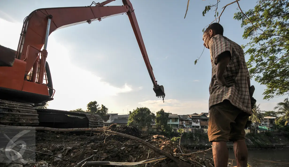 Pria pencari besi bekas tampak lelah saat mencari besi bekas di tumpukan lumpur sisa pengerukan Kali Ciliwung, Jakarta, Jumat (29/7). (Liputan6.com/Yoppy Renato)