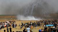 Pasukan Israel menembakkan gas air mata ke arah demonstran Palestina selama bentrokan di perbatasan jalur Gaza (11/5). Sejak aksi digelar kembali pada 30 Maret 2018, sekitar 50 warga Palestina telah tewas oleh tembakan Israel. (AFP Photo/Mohammed Abed)