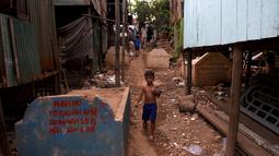 Seorang anak melewati bangunan rumah di sebuah kuburan di Phnom Penh, Kamboja pada 21 Mei 2019. Pemakaman menjadi tempat peristirahatan abadi bagi orang mati, tetapi area pemakaman ini menjelma sebagai tempat tinggal untuk bertahan hidup bagi mereka yang didera kemiskinan. (TANG CHHIN Sothy/AFP)