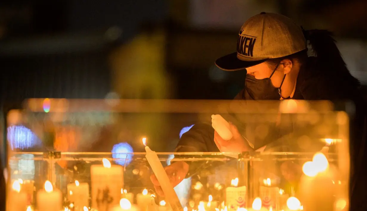 Seorang wanita meletakkan lilin di luar Kuil Jogyesa pada malam sebelum para siswa mengikuti ujian masuk universitas atau suneung, Seoul, Korea Selatan, 17 November 2021. Lebih dari setengah juta siswa akan mengikuti suneung di Korea Selatan. (Anthony WALLACE/AFP)