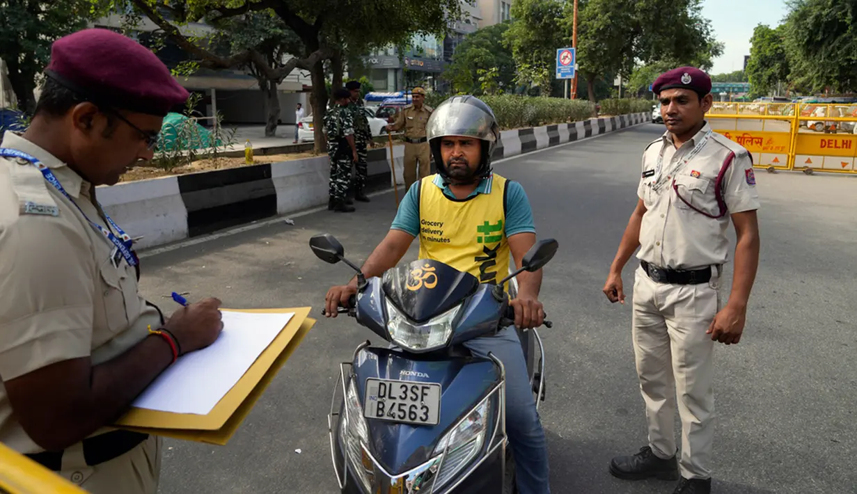 Seorang polisi mencatat detail seorang pengendara skuter yang memasuki zona terlarang menjelang KTT G20 di New Delhi, India, 8 September 2023. (AP Photo/Manish Swarup)