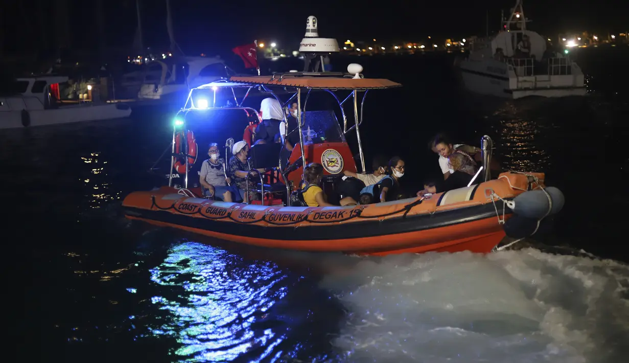 Orang-orang menunggu untuk dievakuasi dengan perahu setelah kebakaran hutan mencapai Pembangkit Listrik Kemerkoy di Milas di barat daya Turki, Rabu (4/8/2021) malam. Kebakaran hutan tersebut sudah memasuki hari ke-7 sejak api pertama muncul pada Rabu (28/7/2021). (AP Photo/Cem Tekkesoglu)