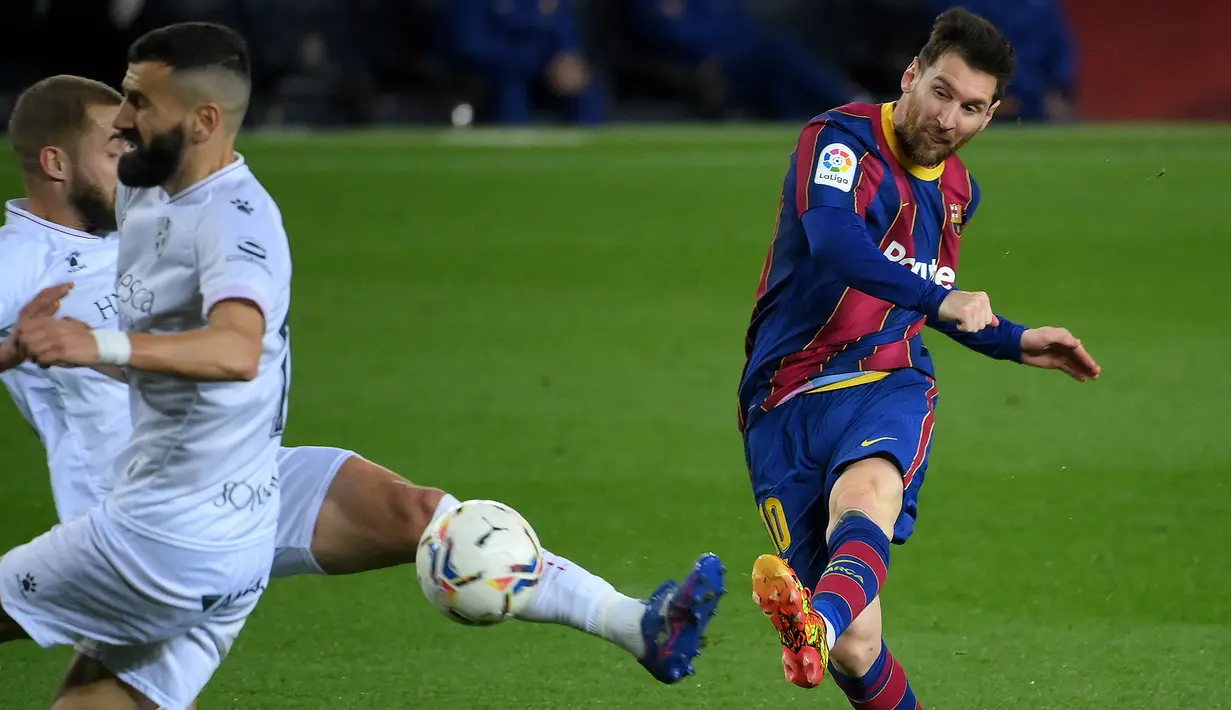 Striker Barcelona, Lionel Messi (kanan) melepaskan tendangan yang berbuah gol keempat timnya ke gawang SD Huesca dalam laga lanjutan Liga Spanyol 2020/2021 pekan ke-27 di Camp Nou Stadium, Barcelona, Senin (15/3/2021). Barcelona menang 4-1 atas SD Huesca. (AFP/Lluis Gene)