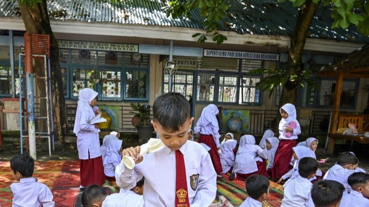 Seorang siswa meminum air selama pembelajaran di luar kelas di Sekolah Dasar Negeri (SDN) 16 Banda Aceh, Aceh, pada 7 Mei 2024. SDN 16 Banda Aceh menggelar pembelajaran di ruang terbuka untuk menghadapi cuaca panas ekstrem. Foto: Chaideer Mahyuddin/AFP