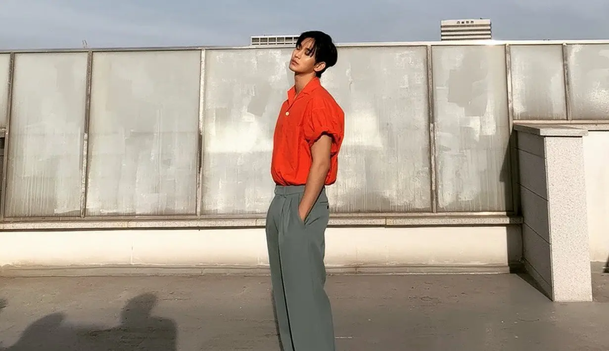 Photoshoot dengan pesona yang tak main-main. Kim Soo Hyun tampil mengenakan kemeja lengan pendek yang digulung ke atas berwarna oranye, dipadunya memakai celana panjang kain berwarna abu-abu dan sneakers putih. [Foto: Instagram/soohyun_k216]