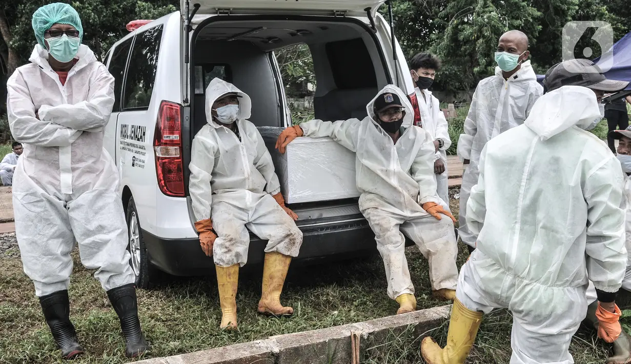 Petugas duduk di dekat peti jenazah saat menunggu antrean pemakaman dengan protokol Covid-19 di TPU Bambu Apus, Jakarta, Kamis (28/1/2021). Pemprov DKI menyiapkan 6 lokasi baru untuk pemakaman jenazah pasien Covid-19 dengan total kapasitas 17.900 petak makam. (merdeka.com/Iqbal S Nugroho)