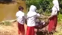 Sebuah video yang memperlihatkan tiga bocah berseragam SD bergelantungan di keranjang untuk menyeberang sungai, viral di media sosial. (Liputan6.com/ Ist)