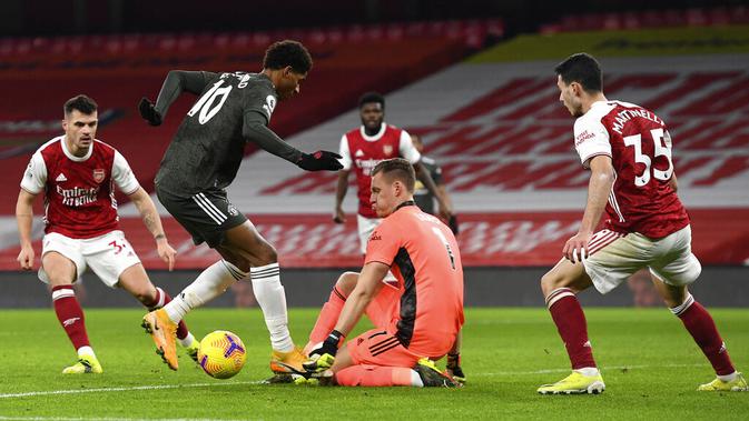 Striker Manchester United, Marcus Rashford, berusaha melewati kiper Arsenal, Bernd Leno, pada laga Liga Inggris di Stadion Emirates, Sabtu (30/1/2021). Kedua tim bermain imbang 0-0. (Andy Rain/Pool via AP)