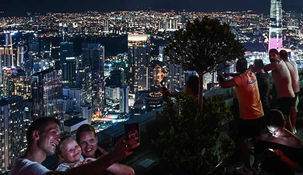 Gambar pada 14 Februari 2019 menunjukkan para turis mengambil gambar pemandangan cakrawala kota dari dek observasi Menara Kuala Lumpur di ibu kota Malaysia. Di sini pengunjung bisa mengamati segala penjuru kota Kuala Lumpur. (Mohd RASFAN / AFP)