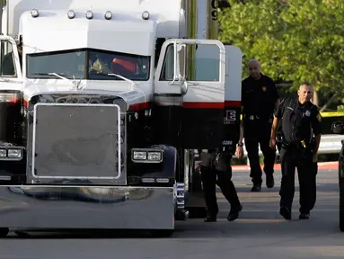 Polisi San Antonio selidiki truk yang berisi sembilan mayat di lapangan parkir sebuah supermarket, Texas, Minggu (23/7).  Selain menemukan korban tewas, 30 orang lainnya juga diselamatkan di dalam truk itu, 17 dalam kondisi kritis. (AP Photo/Eric Gay)