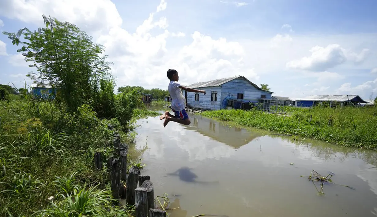 eorang anak laki-laki melompat ke kanal di Cienaga Grande de Santa Marta, Nueva Venecia, Kolombia, 12 Oktober 2021. Sekitar 400 keluarga tinggal di rumah panggung di Cienaga Grande. (AP Photo/Fernando Vergara)