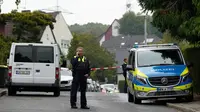 Seorang petugas polisi tampak berbicara di telepon di sebuah jalan di Herdecke, Jerman, pada Selasa (7/10/2025), setelah wali kota terpilih Herdecke, Iris Stalzer, ditemukan dalam kondisi kritis di apartemennya.(Dok. AP/Martin Meissner)