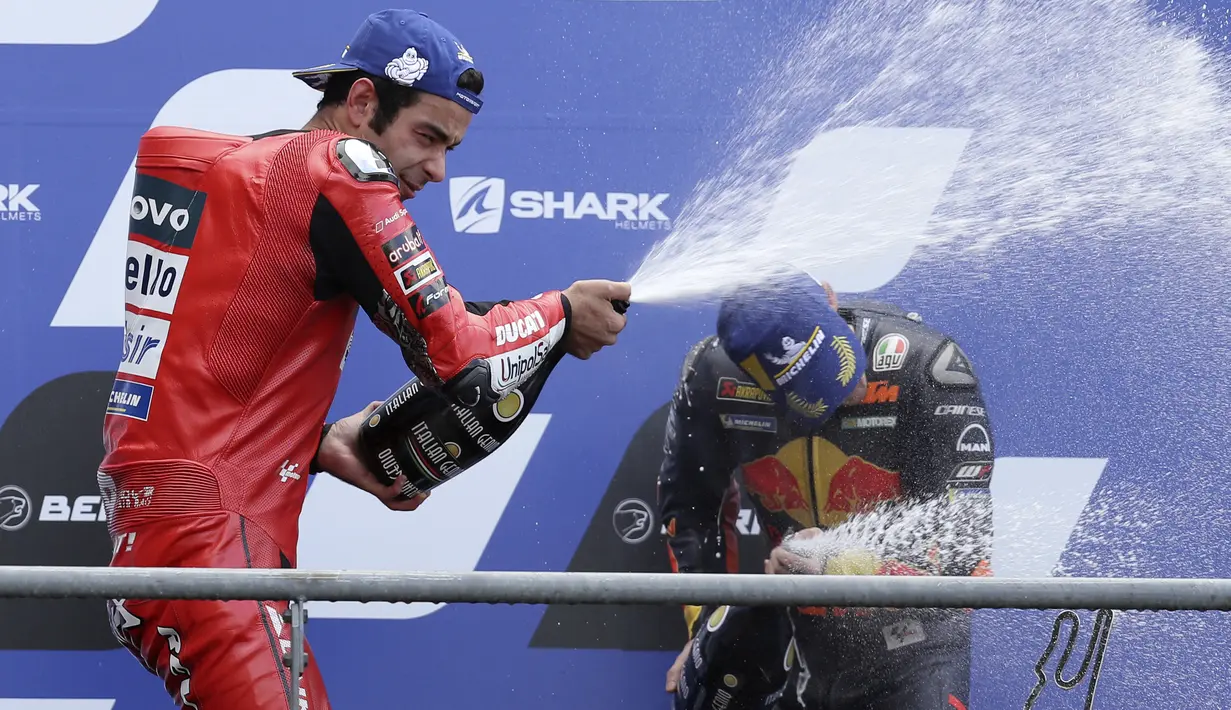 Pembalap Ducati Danilo Petrucci (kiri) menyemprotkan sampanye saat merayakan kemenangannya pada balapan MotoGP Prancis 2020 di Le Mans, Prancis, Minggu (11/10/2020). Danilo Petrucci menjadi yang tercepat disusul Alex Marquez dan Pol Espargaro. (AP Photo/David Vincent)