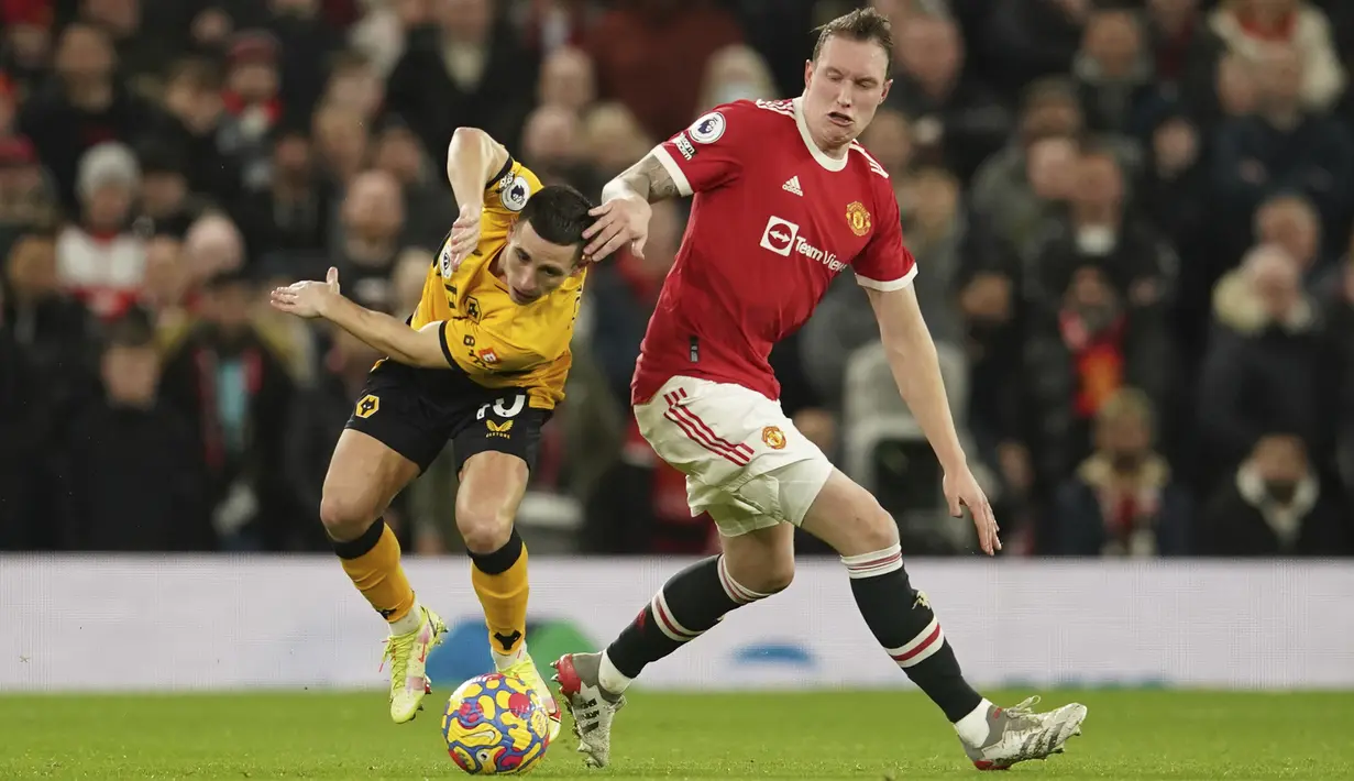Bek Manchester United (MU) Phil Jones berebut bola dengan gelandang Wolverhampton Wanderers Daniel Podencedalam pekan ke-22 Liga Primer Inggris di Old Trafford, Selasa (4/1/2022) dini hari WIB. MU takluk 0-1 saat menjamu Wolves. (AP Photo/Dave Thompson)