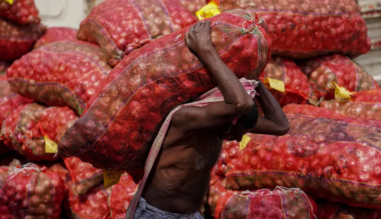 Seorang pekerja membawa sekarung bawang di sebuah pasar grosir di Hyderabad, India, Rabu (1/2/2023). Pemerintah Perdana Menteri India Narendra Modi meningkatkan belanja modal sebesar 33% untuk memacu pertumbuhan ekonomi dan menciptakan lapangan kerja menjelang pemilihan umum tahun depan. (AP Photo/Mahesh Kumar A.)