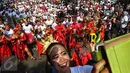 Seorang peserta mengambil gambar dengan latar belakang flashmob 1745 penari di kawasan Senayan Jakarta, Minggu (21/8). Kegiatan bertajuk "Aku Indonesia-Bagimu Negeri Kami Menari" itu merupakan bagian dari perayaan HUT RI ke 71. (Liputan6.com/Fery Pradolo)