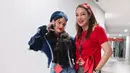 Reisa Broto Asmoro tampil dengan gaya kasual edgy. Ia memadukan blus merah menyala dengan aksen pita di pinggang, loose pants abu-abu, serta sneakers putih. Penampilannya semakin manis dengan bandana merah yang senada dengan blusnya.
