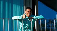 Cristiano Ronaldo yang terjangkit COVID-19 tampak semringah menyaksikan rekan-rekannya di timnas Portugal berlatih dari balkon kamar hotelnya, Selasa (13/10/2020) (AFP/Diogo Pinto)