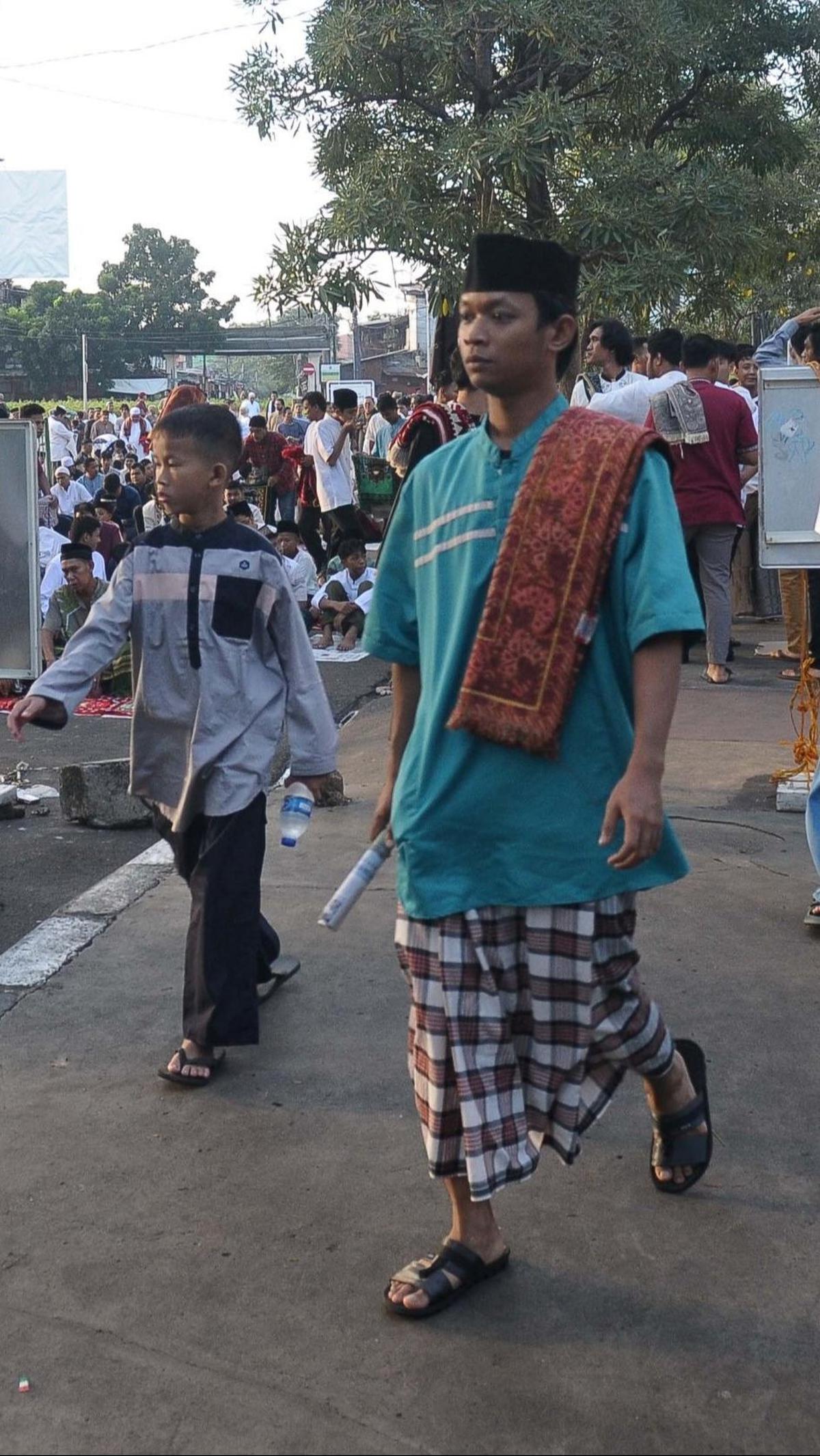 Jemaah yang baru datang terlihat membawa koran yang akan digunakan sebagai alas untuk salat Idulfitri.&nbsp;Foto: merdeka.com / Imam Buhori
