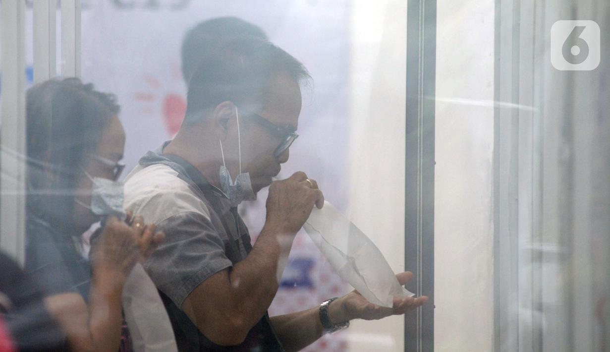 Calon penumpang meniup kantong saat dilakukan tes COVID-19 dengan GeNose C19 di Stasiun Pasar Senen, Jakarta, Selasa (23/2/2021). PT KAI memberikan pelayanan tes COVID-19 dengan GeNose C19 bagi calon penumpang kereta jarak jauh untuk memutus rantai penyebaran virus corona. (merdeka.com/Imam Buhori)