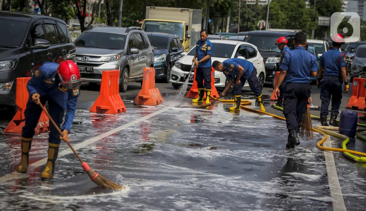 Personil pemadam kebakaran membersihkan tumpah oli di Jalan Veteran depan Gedung Krida Bakti, Jakarta, Kamis (16/1/2020). Sudin Damkar Jakarta Pusat mengerahkan 2 unit mobil damkar dan 10 personil untuk membantu pembersihan bagian jalan yang terkena tumpahan oli. (Liputan6.com/Faizal Fanani)