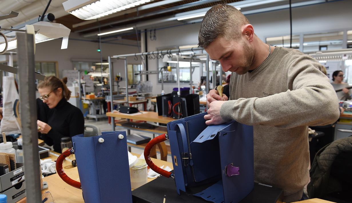 Proses merapikan bagian tas di bengkel produsen barang-barang mewah Hermes di Allenjoie, Perancis, Kamis (5/4). Hermes merupakan brand fashion eksklusif asal Prancis. (SEBASTIEN BOZON/AFP)