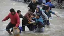 Ribuan migran menyeberangi sungai dengan berpegangan pada seutas tali di perbatasan Yunani-Makedonia, Idomeni, Yunani (14/3/2016). Lebih dari 1.000 migran nekat menembus sungai untuk mencari jalan keluar perbatasan. (Reuters/Stoyan Nenov)