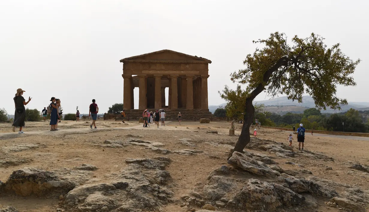 Turis saat mengunjungi Lembah Kuil selama gelombang panas di dekat Agrigento, Sisilia, Italia (11/8/2021). Gelombang panas yang berkelanjutan akan berlangsung hingga akhir pekan dengan suhu diperkirakan mencapai lebih dari 40 derajat Celcius di banyak bagian dari Italia. (AP Photo/Salvatore Cavalli)