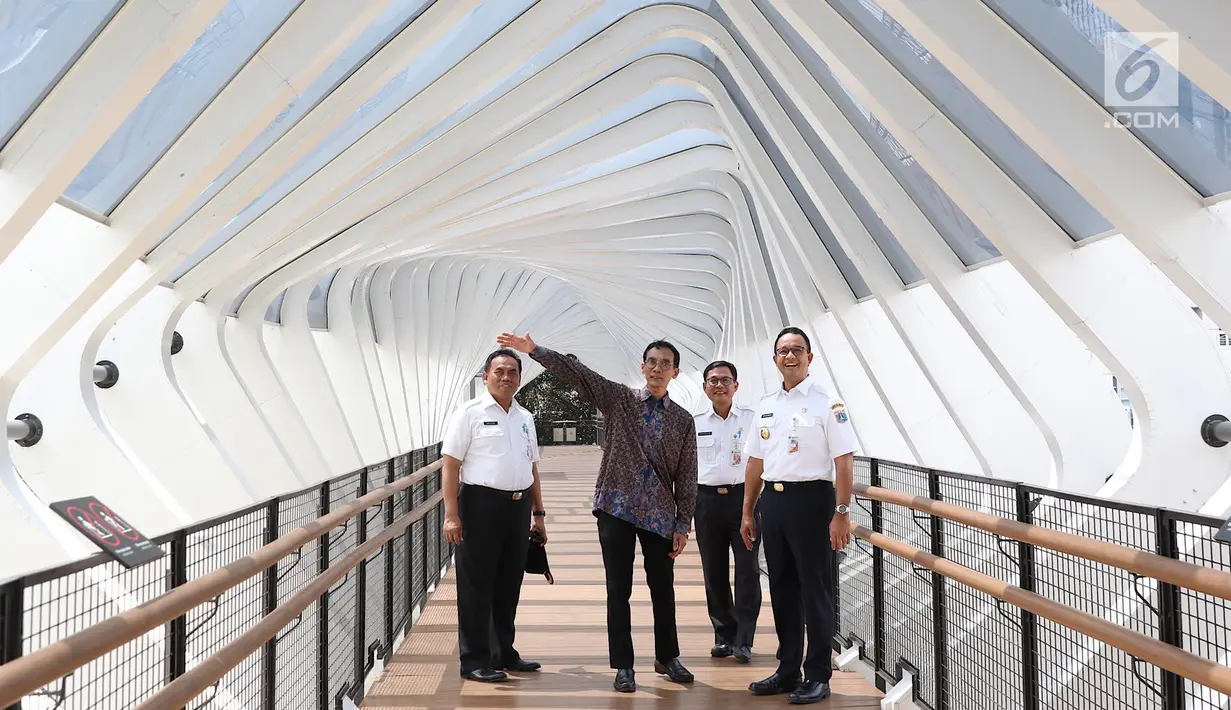 Gubernur DKI Jakarta Anies Baswedan (kanan) mendengarkan penjelasan saat meresmikan jembatan penyeberangan orang (JPO) di Jalan Jenderal Sudirman, Kamis (28/2). Namun, lift JPO masih belum beroperasi ketika diresmikan. (Liputan6.com/Immanuel Antonius)