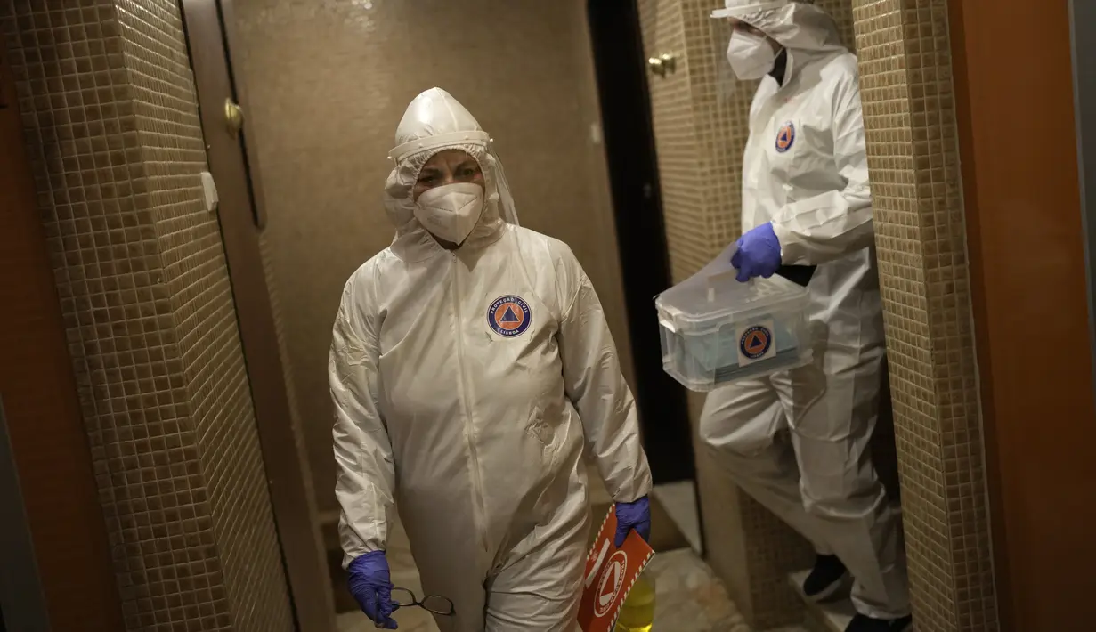 Pekerja Lisbon Civil Protection membawa kotak plastik dengan kertas surat suara yang sudah diisi saat mengunjungi pemilih dalam isolasi COVID-19 di rumah mereka untuk mengambil suara, 25 Januari 2022. Pemilihan umum (Pemilu) di Portugal akan digelar pada 30 Januari mendatang. (AP/Armando Franca)