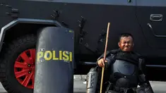 Seorang petugas yang kelelahan bersandar di mobil water cannon yang terparkir di kawasan Patung Kuda, Jakarta, Kamis (21/8/14). (Liputan6.com/Miftahul Hayat)