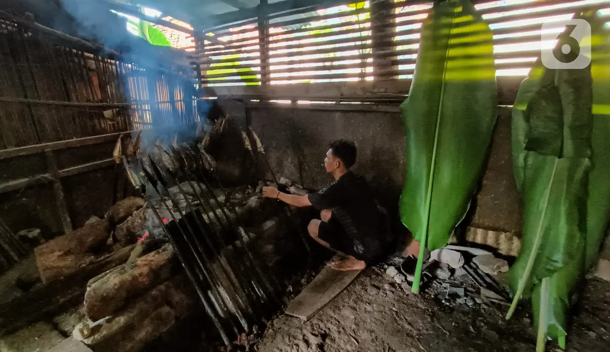 Karyawan mengasap ikan mas menggunakan kayu bakar di Setu Tujuh Muara Sawangan, Depok, Minggu (19/06/2022). Selain ikan, warung makan ini juga mengasap ayam dan jeroan ikan dengan metode yang sama. (Liputan6.com/Fery Pradolo)