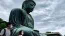 Orang-orang mengenakan masker saat mengunjungi The Great Buddha atau yang biasa disebut Kamakura Daibutsu di kuil Kotoku-in di Kamakura, Prefektur Kanagawa, Jepang, Sabtu (20/6/2020). Patung Buddha dari perunggu yang menjulang dengan tinggi 13,35 meter ini didirikan tahun 1252. (Behrouz MEHRI/AFP)