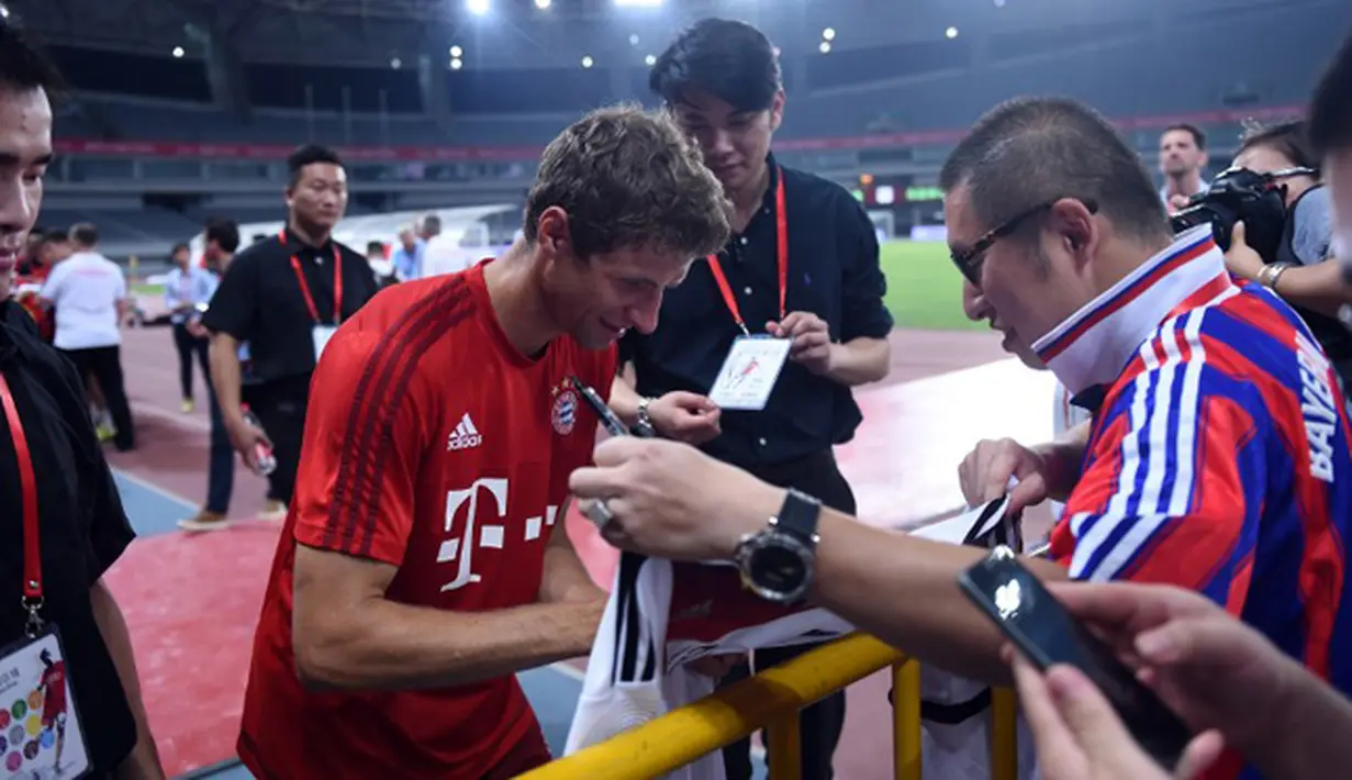 Penyerang Bayern Muenchen, Thomas Mueller menandatangani tanda tangan pengemar usai sesi latihan di Shanghai, China, (19/7/2015). Bayern mengunjungi Cina untuk menggelar Tur Pra-musim. (AFP PHOTO/JOHANNES EISELE)