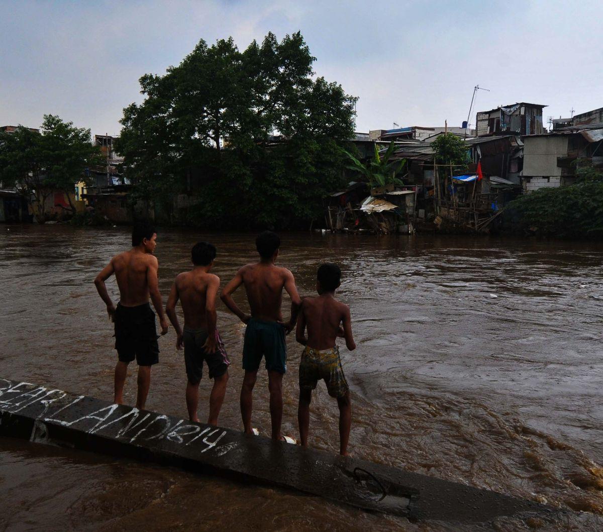 Sejumlah anak bersiap melompat pada aliran Kali Ciliwung yang mengalir deras di kawasan Bukit Duri-Manggarai, Jakarta, Selasa (2/7/2024). Derasnya arus sungai serta tingginya debit air tak menghalangi anak-anak untuk tetap bermain di Kali Ciliwung.&nbsp;M
