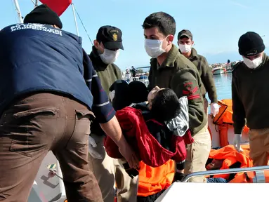 Petugas penyelamat saat menggotong mayat imigran di distrik Altinoluk, Balikesir, Turki, (8/2). Mayat imigran ini ditemukan sedang tenggelam saat mencoba menyeberang dari Turki ke Yunani. (STR / AFP)